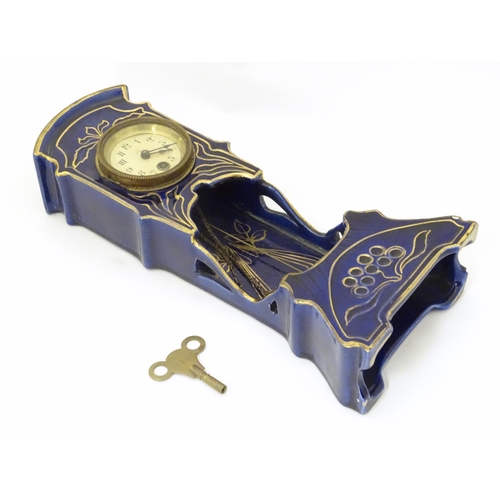 2286 - A Jugendstil mantle clock formed as a ceramic cased long case clock with blue and gilt detail. the d... 