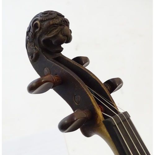 1540 - Musical Instruments: a 19thC German violin, of stained maple construction with carved lion's head sc... 