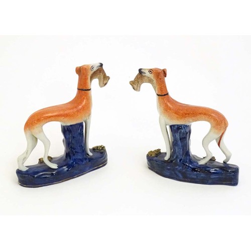 81 - Two Staffordshire pottery greyhound dogs with hares / rabbits in their mouths. Approx. 6