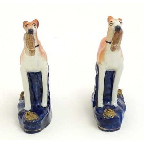 81 - Two Staffordshire pottery greyhound dogs with hares / rabbits in their mouths. Approx. 6