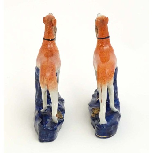 81 - Two Staffordshire pottery greyhound dogs with hares / rabbits in their mouths. Approx. 6