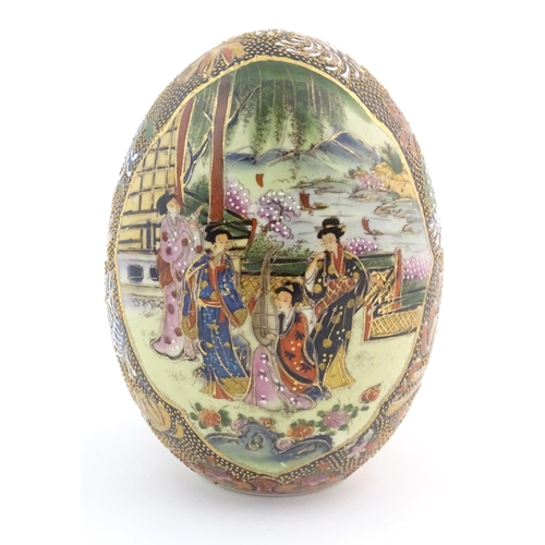 56 - A Japanese model of an egg decorated with four ladies on a garden terrace playing musical instrument... 