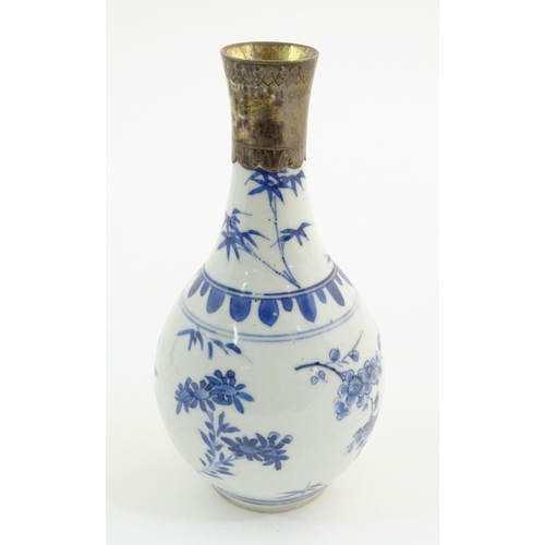 64 - An Oriental blue and white bottle vase with silver plate collar, the body decorated with prunus blos... 