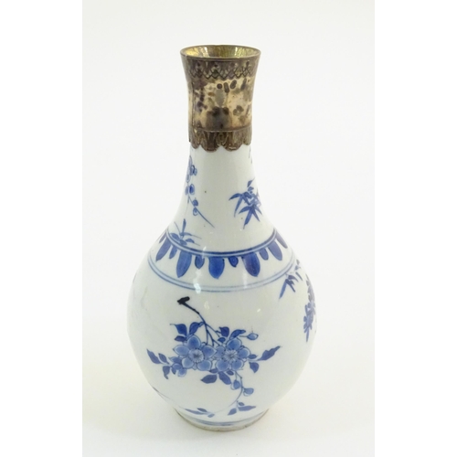 64 - An Oriental blue and white bottle vase with silver plate collar, the body decorated with prunus blos... 