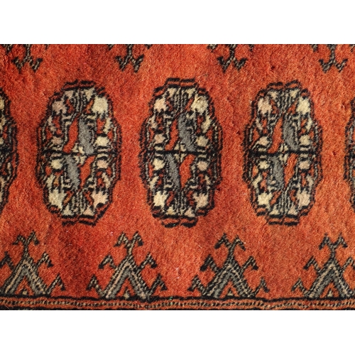 1390 - Carpet / Rug : A red ground rug with banded medallion motifs. Approx. 115