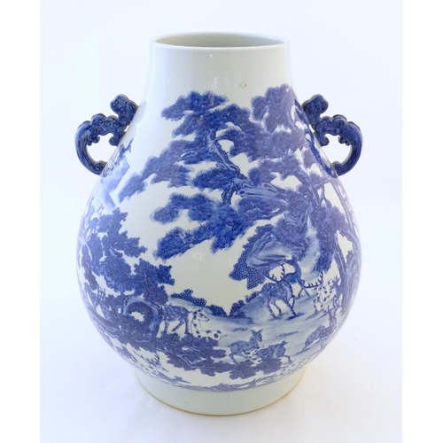 A large Chinese Hu vase with scrolled twin handles, the body decorated in blue and white with the Hundred Deer pattern, depicting deer in a mountainous wooded landscape. Character marks under. Approx. 17 1/2" high