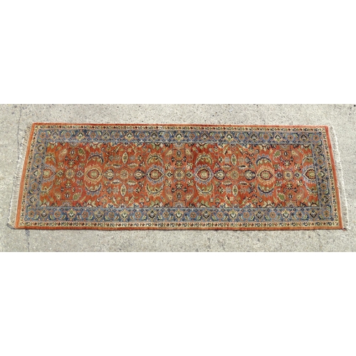 1387 - Carpet / Rug : A runner, the salmon ground with floral and foliate detail and decorative blue and cr... 