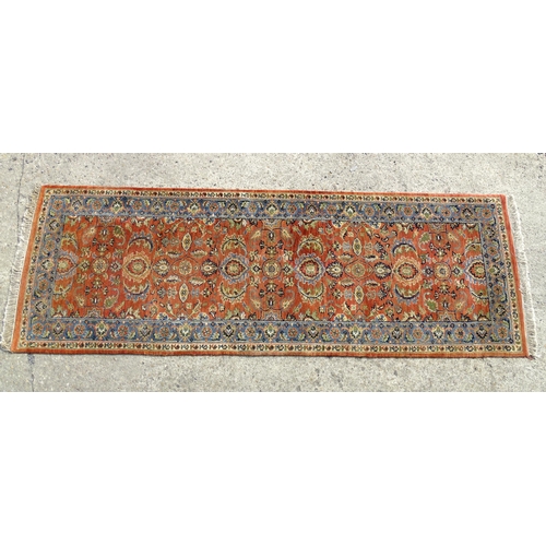 1387 - Carpet / Rug : A runner, the salmon ground with floral and foliate detail and decorative blue and cr... 