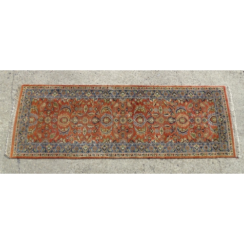 1387 - Carpet / Rug : A runner, the salmon ground with floral and foliate detail and decorative blue and cr... 