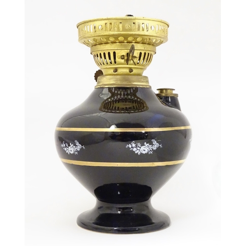 1339 - A Gemfine oil lamp, the black  body decorated with gold banding and white floral vignettes, fitted w... 