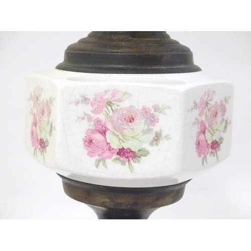 1348 - An early 20thC table oil lamp, the brass column with ceramic mid section decorated with roses and su... 