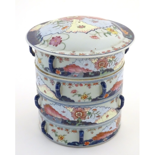 7 - A Chinese four tier lidded porcelain food container of cylindrical form decorated with flowers and f... 