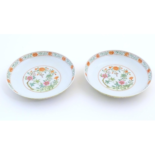 11 - A pair of Chinese plates / dishes with central roundels depicting flowers and a foliate border. The ... 