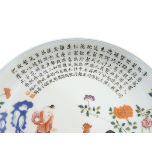 21 - A Chinese famille rose plate decorated with a figure, a cockerel, hen and chicks in a garden with fl... 