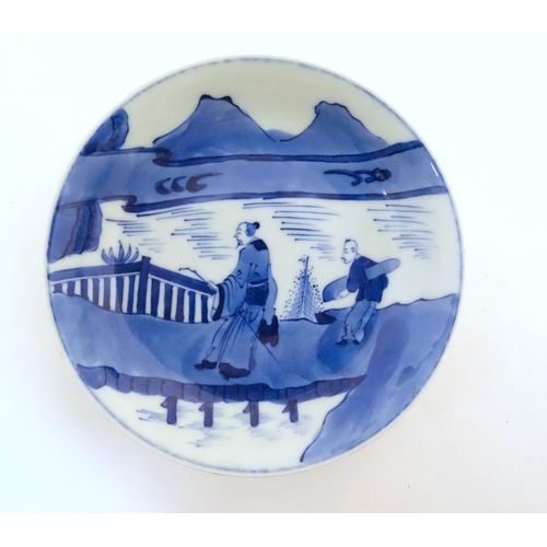 27 - A Chinese blue and white dish with two figures crossing a bridge in a mountain landscape. Character ... 