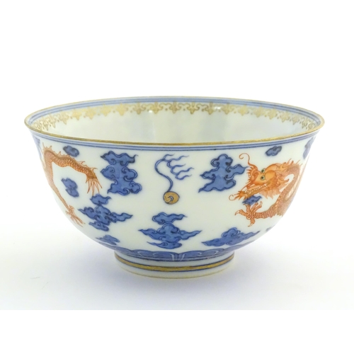 38 - A Chinese blue and white dragon bowl decorated with red dragons, flaming pearl and stylised clouds. ... 
