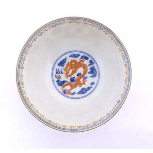 38 - A Chinese blue and white dragon bowl decorated with red dragons, flaming pearl and stylised clouds. ... 