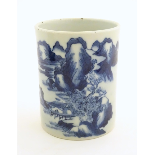 49 - A Chinese blue and white brush pot of cylindrical form decorated with a stylised landscape with moun... 