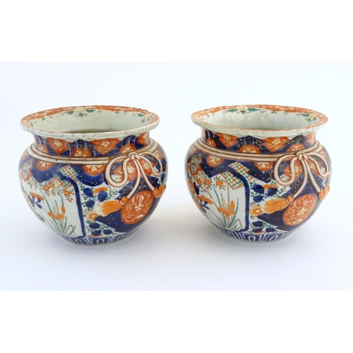 69 - A pair of Oriental planters / jardinieres decorated in the Imari with flowers, foliage and tassel bo... 