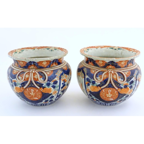 69 - A pair of Oriental planters / jardinieres decorated in the Imari with flowers, foliage and tassel bo... 