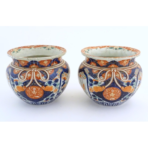 69 - A pair of Oriental planters / jardinieres decorated in the Imari with flowers, foliage and tassel bo... 