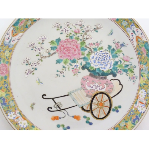 73 - A Chinese famille rose charger depicting a cart carrying a vase of blossoming flowers, the border wi... 