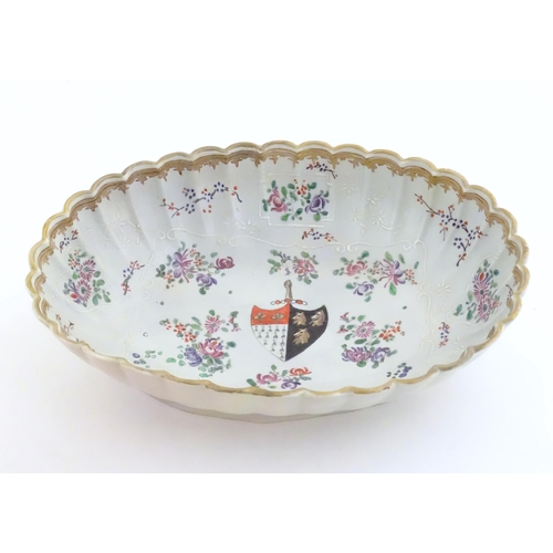 76 - A Chinese export bowl of oval form with scalloped edge, decorated with flowers, foliage and armorial... 