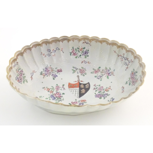 76 - A Chinese export bowl of oval form with scalloped edge, decorated with flowers, foliage and armorial... 