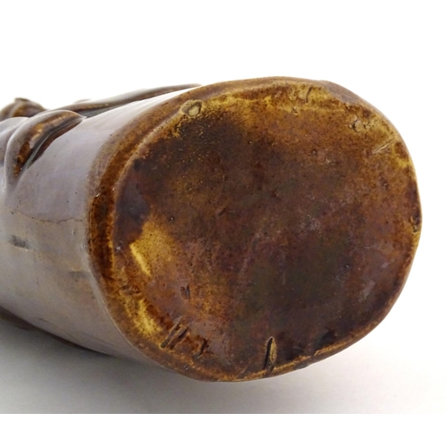 169 - A Victorian treacle glazed spirit flask modelled as Old Tom, a man sat on a barrel with a jug and ta... 