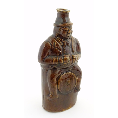 169 - A Victorian treacle glazed spirit flask modelled as Old Tom, a man sat on a barrel with a jug and ta... 