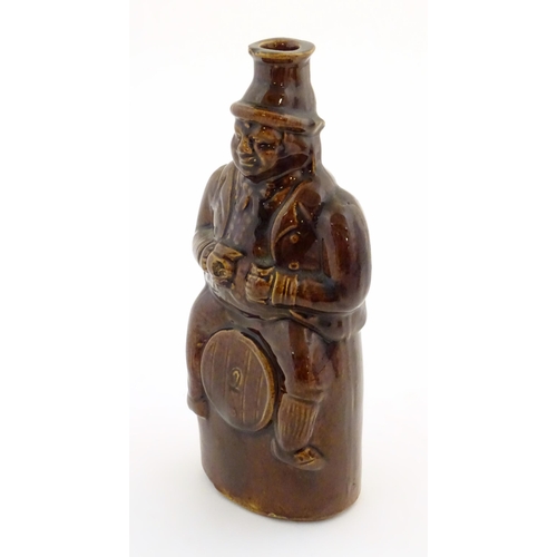 169 - A Victorian treacle glazed spirit flask modelled as Old Tom, a man sat on a barrel with a jug and ta... 