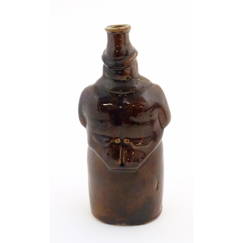 169 - A Victorian treacle glazed spirit flask modelled as Old Tom, a man sat on a barrel with a jug and ta... 