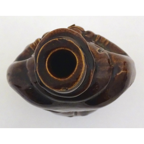 169 - A Victorian treacle glazed spirit flask modelled as Old Tom, a man sat on a barrel with a jug and ta... 