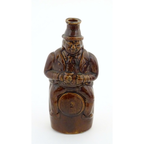 169 - A Victorian treacle glazed spirit flask modelled as Old Tom, a man sat on a barrel with a jug and ta... 