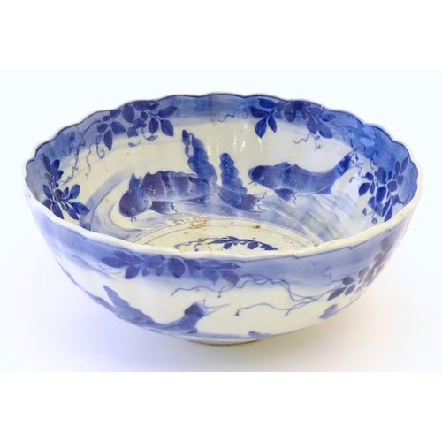 22 - A large Chinese blue and white bowl with a scalloped edge, the body decorated with koi carp fish amo... 