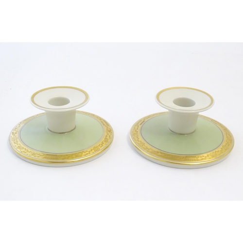 142 - A pair of Royal Copenhagen candlesticks of squat circular form with gilt highlights. Marked under. A... 