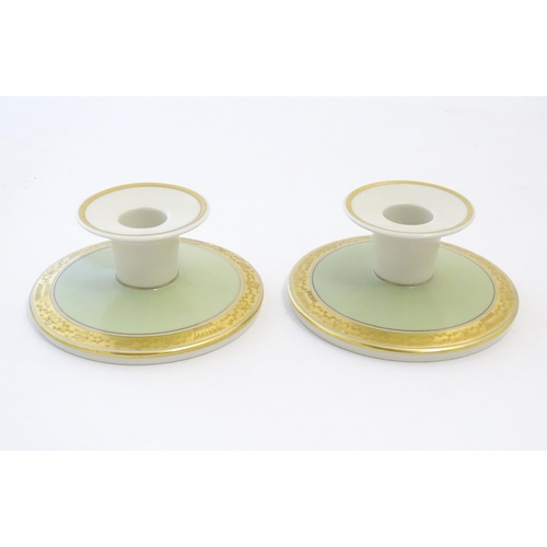 142 - A pair of Royal Copenhagen candlesticks of squat circular form with gilt highlights. Marked under. A... 