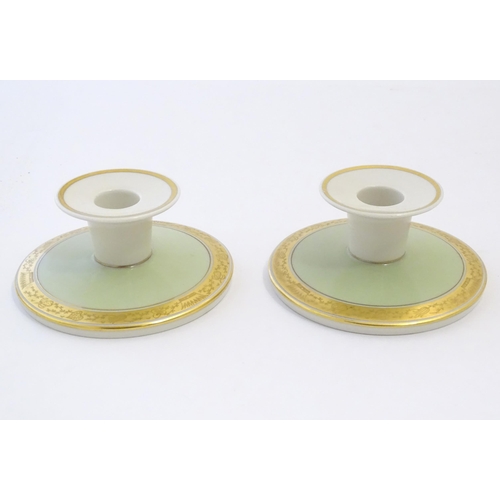 142 - A pair of Royal Copenhagen candlesticks of squat circular form with gilt highlights. Marked under. A... 