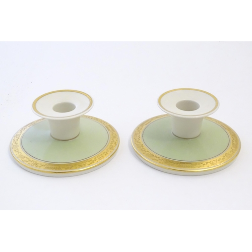 142 - A pair of Royal Copenhagen candlesticks of squat circular form with gilt highlights. Marked under. A... 