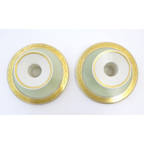 142 - A pair of Royal Copenhagen candlesticks of squat circular form with gilt highlights. Marked under. A... 