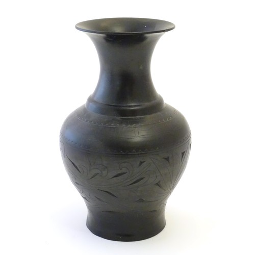 86 - An Oriental black vase of baluster form with a flared rim and incised foliate detail. Approx. 10 1/2... 