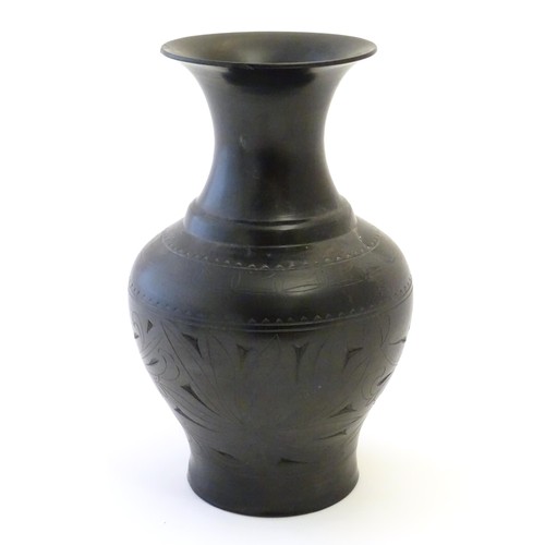 86 - An Oriental black vase of baluster form with a flared rim and incised foliate detail. Approx. 10 1/2... 