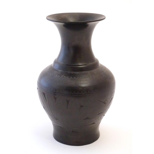 86 - An Oriental black vase of baluster form with a flared rim and incised foliate detail. Approx. 10 1/2... 