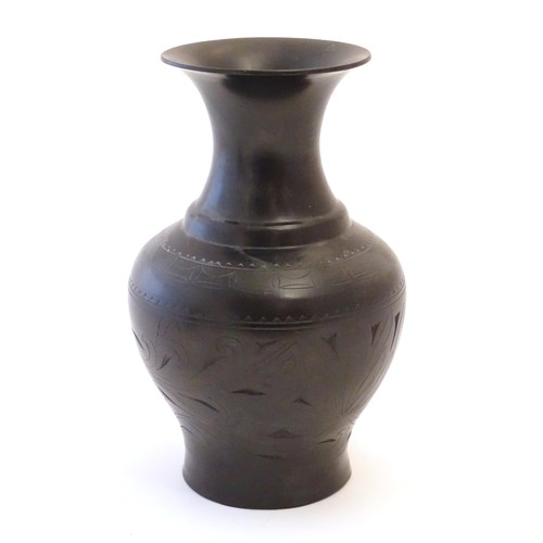 86 - An Oriental black vase of baluster form with a flared rim and incised foliate detail. Approx. 10 1/2... 