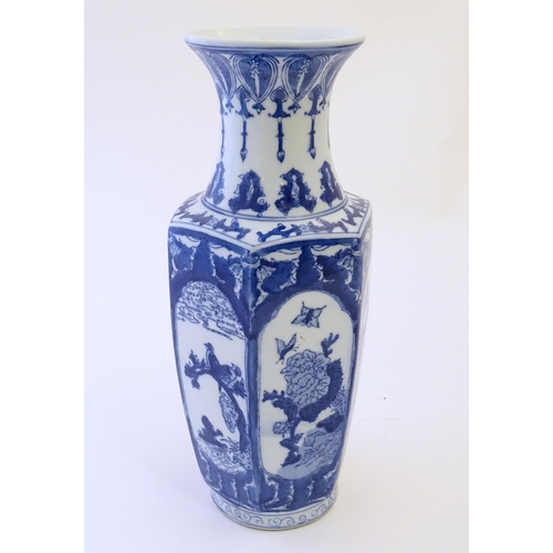 81 - An Oriental blue and white vase with panelled decoration depicting landscapes, birds perched on bran... 