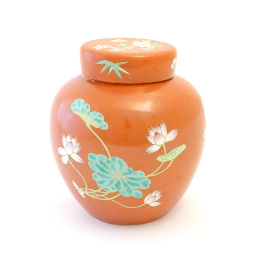 77 - A Chinese ginger jar with an orange ground decorated with flowers and foliage. Character marks under... 