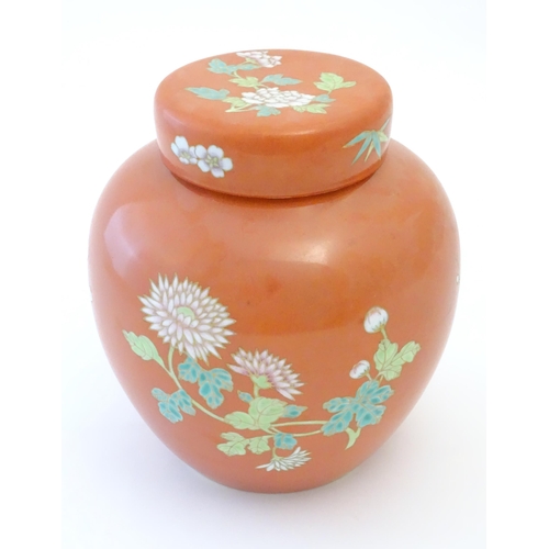 77 - A Chinese ginger jar with an orange ground decorated with flowers and foliage. Character marks under... 