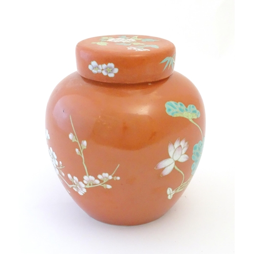 77 - A Chinese ginger jar with an orange ground decorated with flowers and foliage. Character marks under... 