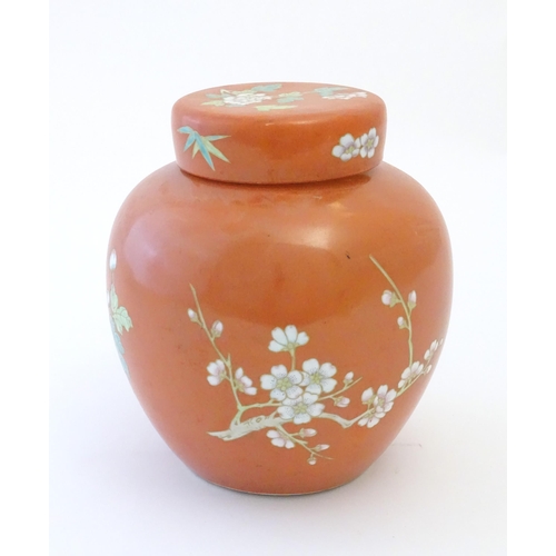 77 - A Chinese ginger jar with an orange ground decorated with flowers and foliage. Character marks under... 