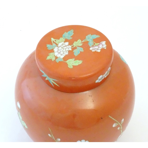 77 - A Chinese ginger jar with an orange ground decorated with flowers and foliage. Character marks under... 